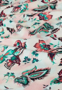 Floral fabric with pink background, featuring vibrant green and red patterns. Smooth texture with intricate leaf and flower designs.