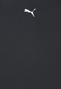 Svart sportskjorte laget av glatt, elastisk stoff; har en hvit Puma-logo øverst til venstre. Enkel design, tettsittende fasong.