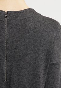 Ciemnoszary sweter z gładkiej dzianiny, okrągłym dekoltem i krótkim zamek na plecach.