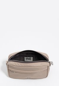 Beżowa prostokątna torebka na ramię z srebrnym zamkiem błyskawicznym, czarną metką wewnętrzną z napisem BIMBA Y LOLA oraz małą przednią kieszenią z metalowym detalem.