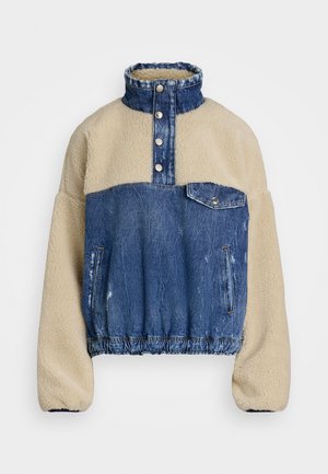 Džínová a fleecová mikina s vysokým golierom, svetlo béžový fleecový vrch, modré džínsy, zapínanie na gombíky a elastický pás.