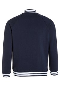 Chaqueta bomber azul marino con cuello, puños y dobladillo de canalé a rayas blancas y azul marino, vista desde la parte posterior.