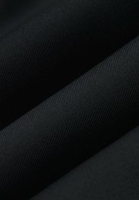 Czarna tkanina o teksturze z delikatnym połyskiem, prezentująca skośny wzór tkania, złożona, aby podkreślić głębię i jakość materiału.