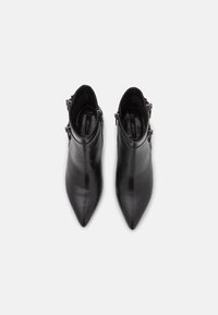 Par de botas de piel negras de punta afilada hasta el tobillo con hebillas laterales, mostradas desde una vista superior sobre un fondo blanco.