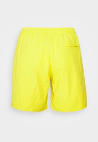 Bright yellow shorts made of lightweight fabric, featuring an elastic waistband and a single back pocket with a flap.