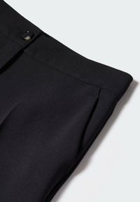 Pantalon noir en tissu lisse et structuré. Doté d'une fermeture à bouton, d'un devant plissé et d'une coupe ajustée. Sans motifs ni accents visibles.
