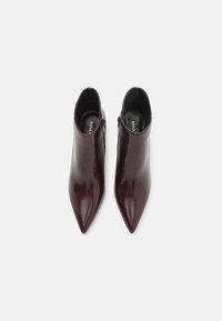 Burgunderfarbene Leder-Stiefeletten mit spitz zulaufender Zehenpartie, die über eine glatte Textur und einen seitlichen Reißverschluss zum Verschließen verfügen.