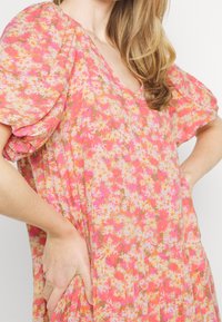 Blumenkleid mit Puffärmeln, lebhaften Rosa- und Orangetönen, mit einem V-Ausschnitt und einem gestuften, geplissten Design. Leichter Stoff.