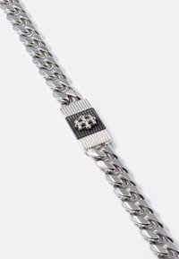 Bracciale in argento a catena curb con chiusura rettangolare, caratterizzata da dettagli a strisce nere e argento e un motivo croce in rilievo.