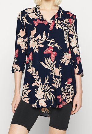 Blouse marine avec un motif floral et de papillons en rose et crème. Comprend un col, des boutons et des manches trois-quarts. Tissu léger.