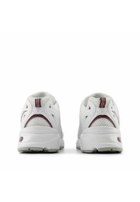 Sneakers atletici bianchi con accenti in rete e dettagli color bordeaux. Tacco rotondo, colletto imbottito e suole testurizzate per una migliore aderenza.