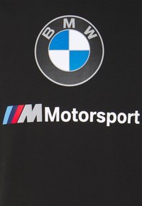 Logo del emblema redondo de BMW en negro, blanco y azul, con el texto "M Motorsport" abajo y franjas rojas, azules y azul claro sobre un fondo negro.