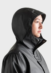 Black waterproof jacket with a fitted hood, featuring smooth texture, zipper closure, and snap buttons along the collar.