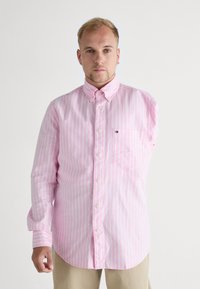 Pink striped button-up shirt with a collar, featuring a left chest pocket and a logo detail. Made of lightweight fabric with a smooth texture.