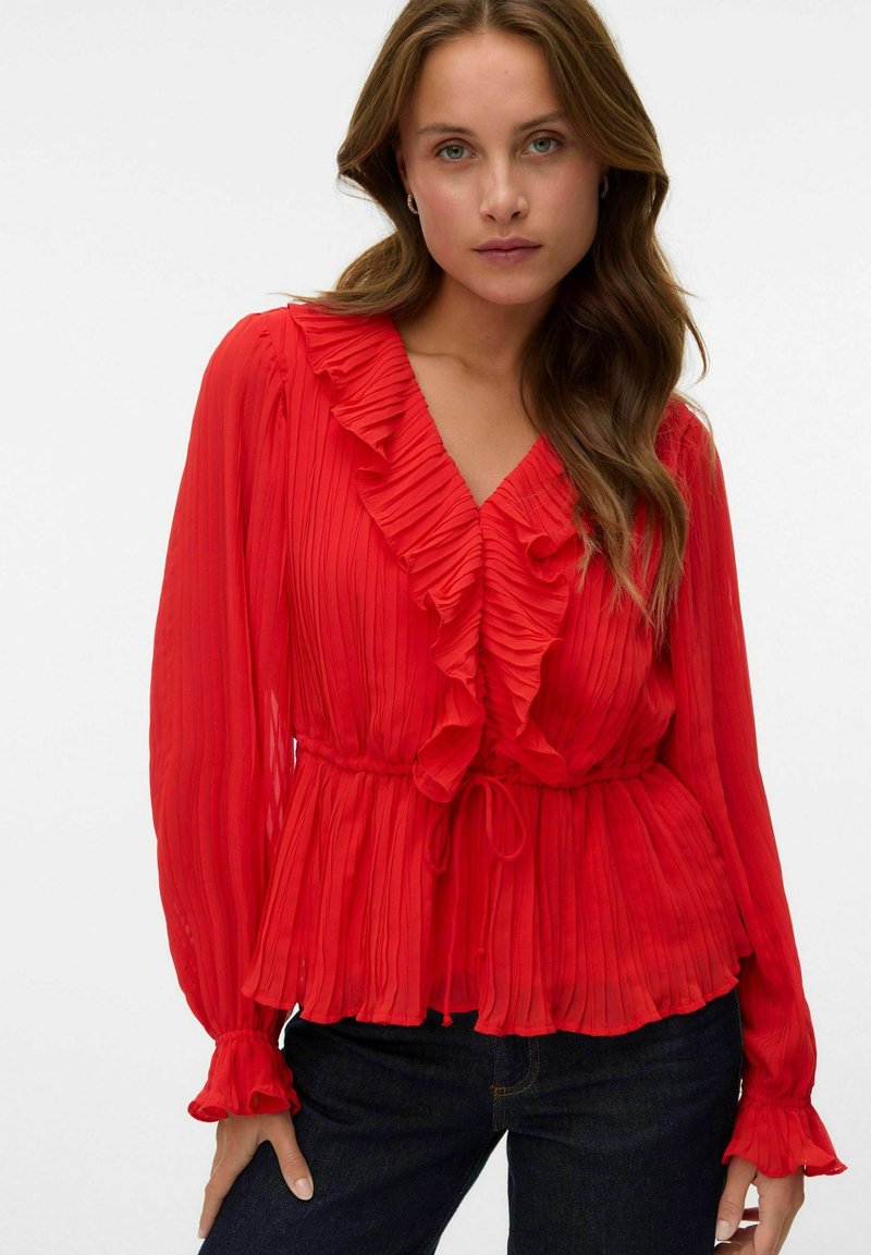 Blusa plissettata rossa con dettagli a volant lungo il collo e le maniche, dotata di una vita annodata e maniche lunghe e fluide.
