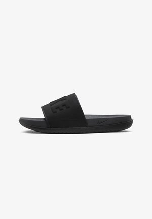 Black slide sandals with a textured strap and embossed logo. Made of synthetic material with a cushioned sole and minimal tread pattern.