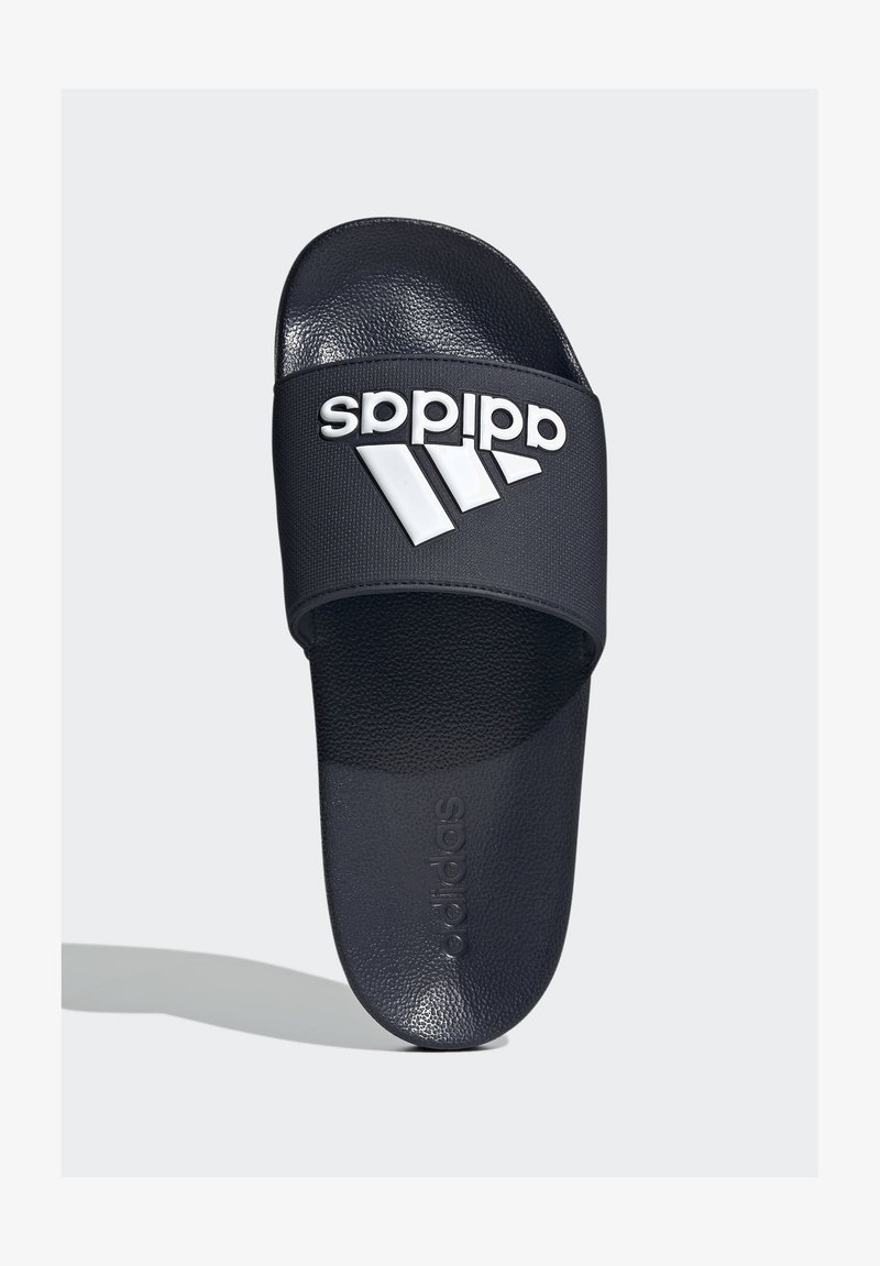 Black slide sandal with textured strap, featuring a white Adidas logo and three diagonal stripes on the upper surface. Soft footbed.