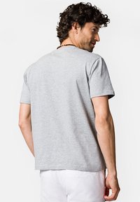 Szara koszulka z okrągłym dekoltem i krótkimi rękawami, wykonana z miękkiej mieszanki bawełny, charakteryzująca się luźnym krojem i gładką teksturą. Pokazany widok z tyłu.