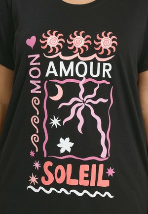 Schwarzes T-Shirt mit pinken und weißen abstrakten Sonnen, Sternen, Mond, Blumen und dem Text "MON AMOUR SOLEIL" in fettgedruckten, stilisierten Schriftarten.