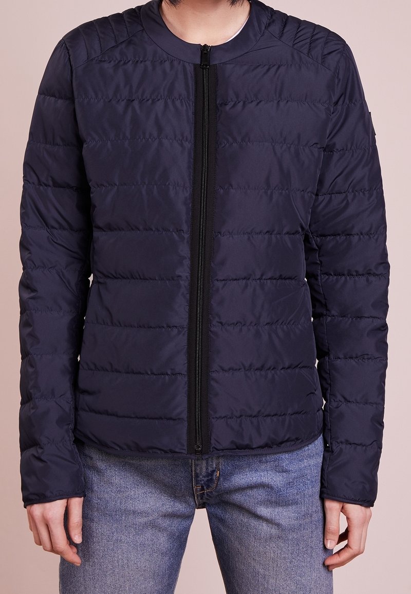 Navy padded jacket with a zip front, round neckline, and quilted texture. Features long sleeves and a fitted silhouette.