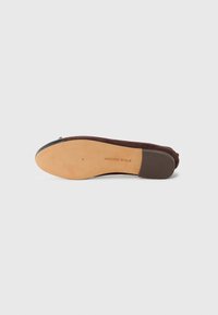 Brown suede flat shoe with a rounded toe, black leather accents, flexible rubber sole, and a minimalistic design.