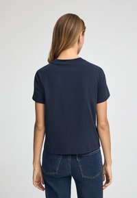 Camiseta de algodón de manga corta en color azul marino, con un corte relajado y un escote redondo, costuras visibles y una textura lisa.