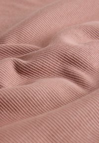 Material texturat în nuanță de roz pal, cu un model nervurat care creează valuri ondulate. Suprafață netedă cu variații subtile ale intensității culorii.