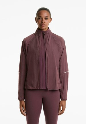 Leichte, pflaumenfarbene Jacke mit hohem Kragen, durchgehendem Reißverschluss und reflektierenden Akzenten. Hergestellt aus strukturiertem Stoff. Figurbetontes Design mit langen Ärmeln.