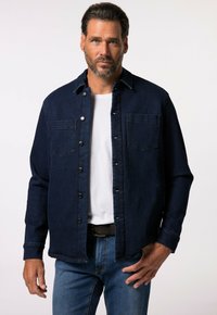 Tmavě modrá džínová košile s knoflíkovým zapínáním, dvěma náprsními kapsami a špičatým límcem. Nositá přes bílé tričko, kombinovaná s modrými džíny.