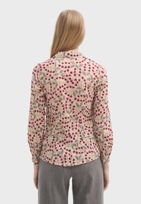 Blomstret bluse i cremefarvet med pink og grønne mønstre, lange ærmer, knaplukket krave, tekstureret stof og samlet detalje bagpå.