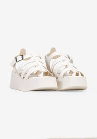 Sandalias de plataforma blancas con un diseño trenzado, detalle de hebilla, textura suave y una suela gruesa y plana con una ligera curva.