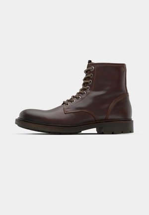 Braune Leder-Ankle-Boots mit einer abgerundeten Zehe, sechs metallischen Ösen, kontrastierenden Nähten und einer strukturierten Gummisohle.