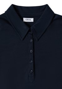 Polo bleu marine foncé avec col et patte à quatre boutons, arborant une étiquette blanche avec le nom de la marque "CECIL" à l'intérieur de l'encolure.