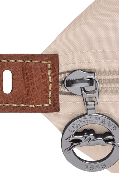 Beige fabric with a textured brown leather tab, featuring a silver zip and a round gray logo tag with a leaping dog design.