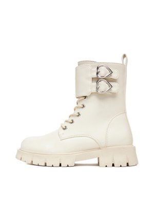 Biały skórzany botek za kostkę na masywnej podeszwie, z boczną klamrą ozdobioną sercowymi akcentami oraz klasycznym sznurowaniem.