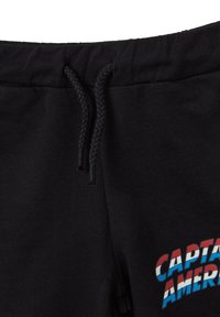 Los pantalones de chándal negros presentan un cordón trenzado y un gráfico multicolor de "CAPITÁN AMÉRICA" en el lado izquierdo, fabricados en suave algodón.