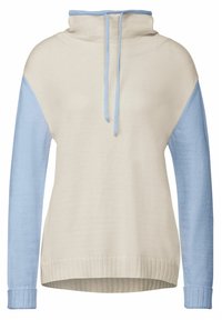 Stickad pullover med en beige kropp och ljusblå ärmar. Har en hög krage, dragsko och ribbade mudd- och nederkanter. Slät textur.