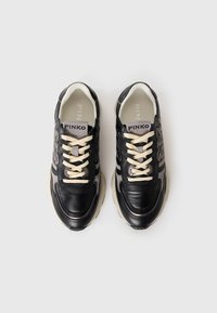 Zwarte leren en suède sneakers met beige veters, voorzien van een gewatteerde kraag en grijze accenten, gestructureerde oppervlakken en een logo op de tong.