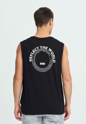 Sort ærmeløs t-shirt med hvid tekst på bagsiden, med frasen "REFLECT THE WORLD" i en cirkulær opstilling.