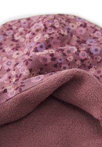 Cappello realizzato in tessuto a fantasia floreale viola con fodera in morbido pile rosa. Forma arrotondata con un bordo flessibile.