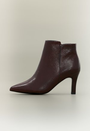 Bottine en cuir marron foncé texturé avec bout pointu et talon fin de hauteur moyenne sur fond neutre.