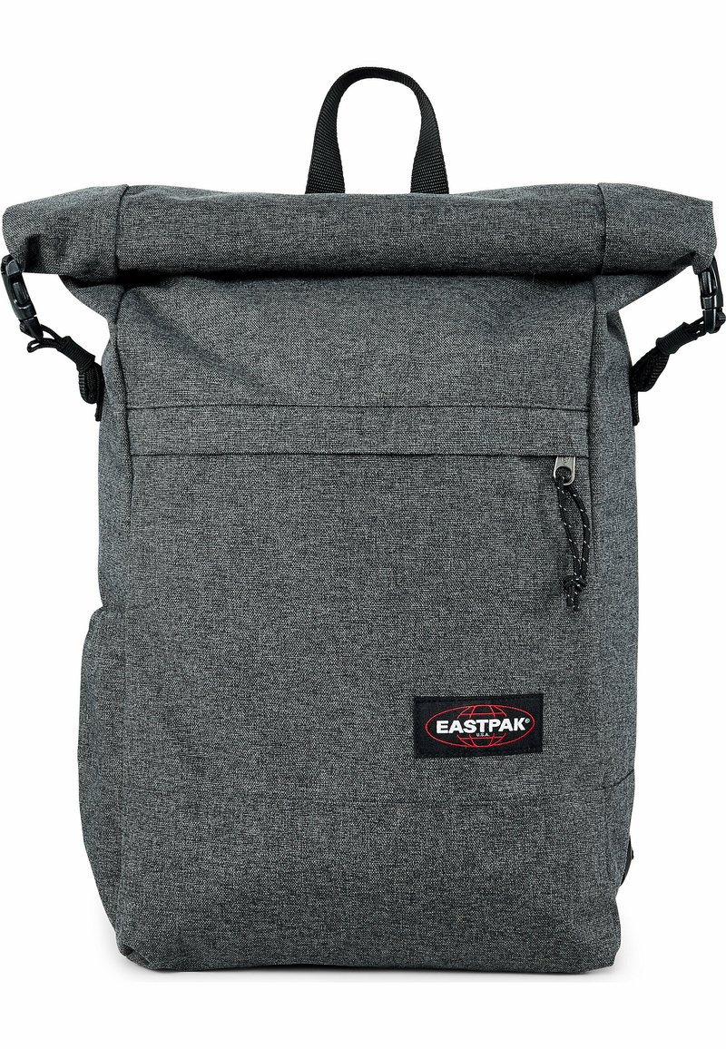 Zaino grigio con chiusura a rotolo realizzato in tessuto testurizzato, dotato di tasca frontale con zipper, spallacci regolabili e maniglia superiore per il trasporto.