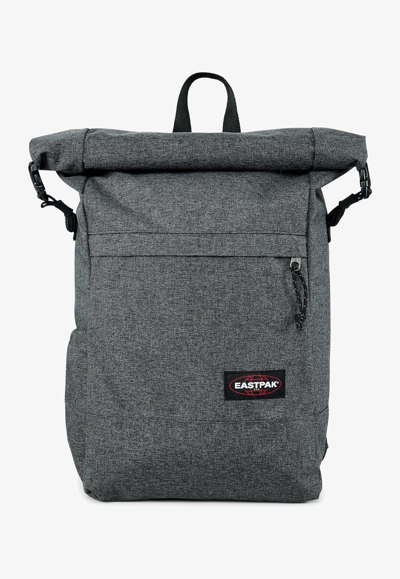 Zaino grigio con chiusura a rotolo realizzato in tessuto testurizzato, dotato di tasca frontale con zipper, spallacci regolabili e maniglia superiore per il trasporto.