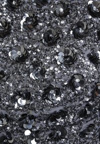 Black sequined fabric featuring circular and floral-shaped sequins, with a metallic sheen, layered for texture and visual depth.