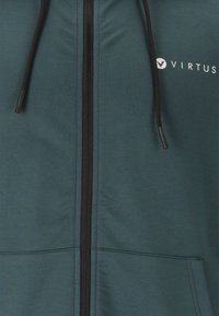 Turkos zip-up hoodie tillverkad av mjukt tyg, med en framzipper, dragskohuva och vit "VIRTUS" logo på övre bröstet.