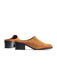 Mules de tacón en ante color canela con punta redondeada y tacón bajo en bloque negro. Textura suave y diseño minimalista sin adornos visibles.