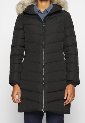 Svart puffrig jacka med dragkedja fram, horisontellt quiltat mönster, avtagbar huva med foder i päls, sidofickor och ribbade ärmslut.