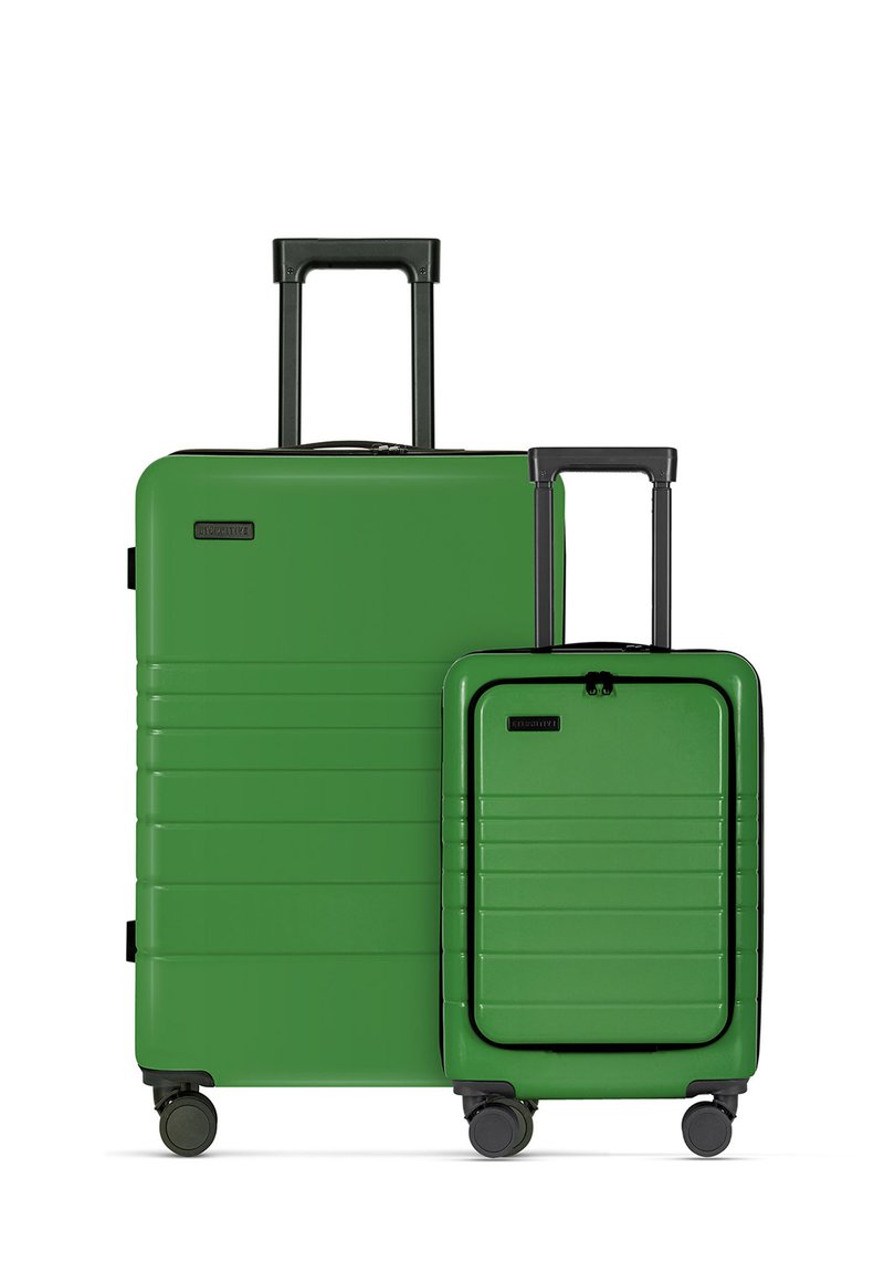 Twee groene kofferstukken, een grote en een kleine, met een gladde harde schaal, horizontale ribbels, telescopische handvatten en rollen.