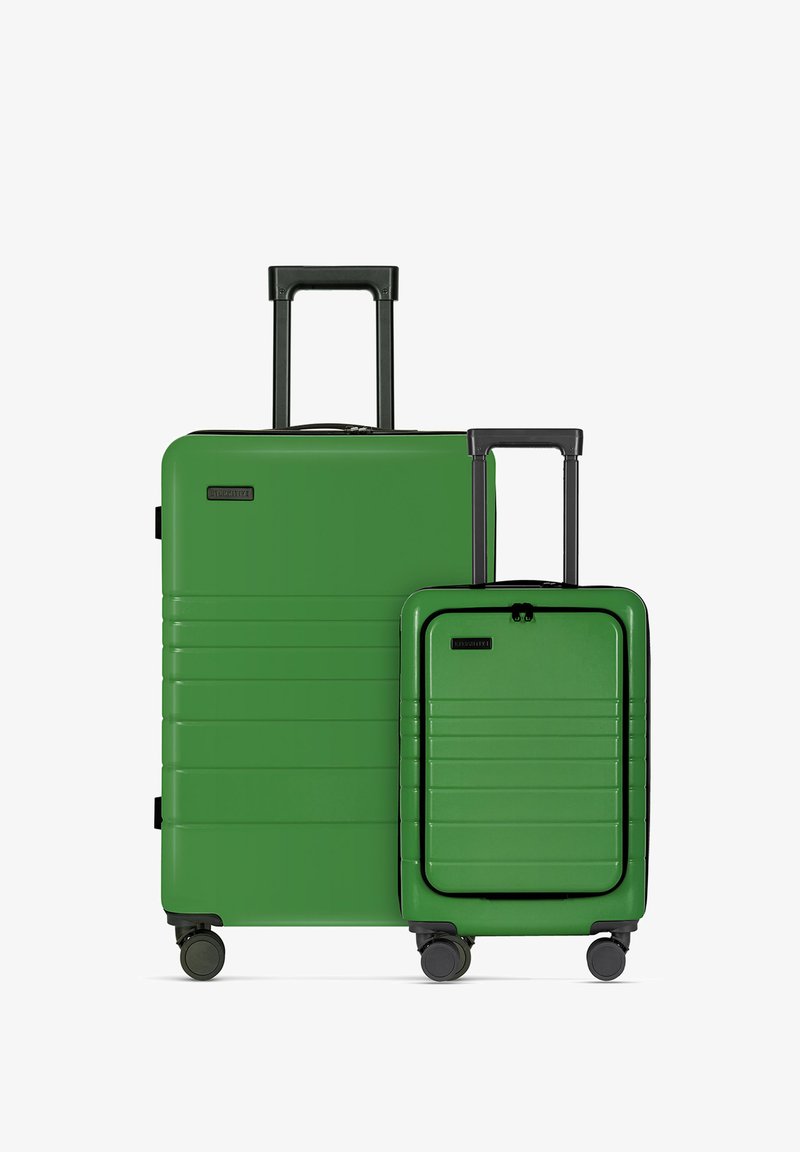 Twee groene kofferstukken, een grote en een kleine, met een gladde harde schaal, horizontale ribbels, telescopische handvatten en rollen.