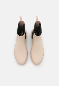 Botas de tobillo de goma beige con una textura suave, paneles laterales elásticos y tiradores. Forro interior negro. Talla 37 marcada en el interior.